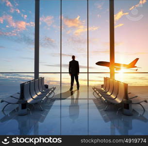 Business travel. Businessman at airport looking at airplane taking off