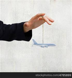 Business travel. Close up of businessman hand holding airplane model on rope