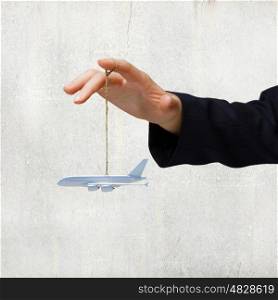 Business travel. Close up of businessman hand holding airplane model on rope