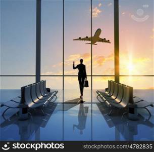 Business travel. Image of woman in airport looking at taking off airplane