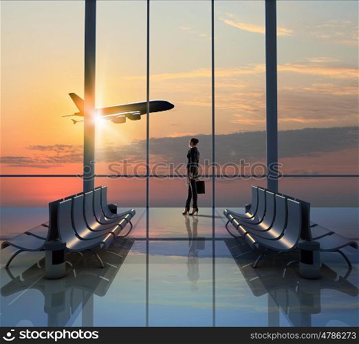 Business travel. Image of woman in airport looking at taking off airplane