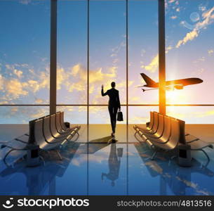 Business travel. Image of woman in airport looking at taking off airplane