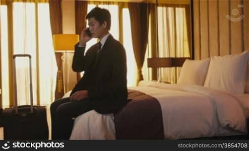 Business travel, people traveling, working in hotel room, manager. Asian businessman, man at work, talking on cell phone, mobile telephone. Career and success. 12of21