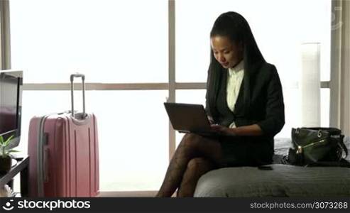 Business travel, people working in hotel room, happy multiethnic manager. Black businesswoman, busy girl talking on phone, woman at work, using pc, laptop, computer, notebook for internet, email