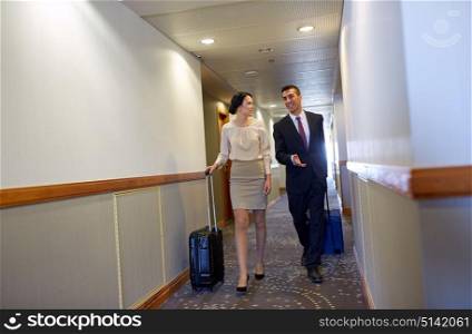business trip and people concept - man and woman with travel bags at hotel corridor. business team with travel bags at hotel corridor
