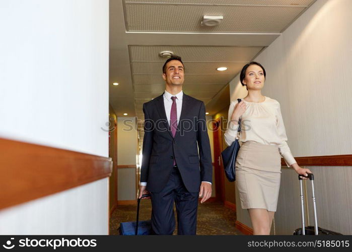 business trip and people concept - man and woman with travel bags at hotel corridor. business team with travel bags at hotel corridor