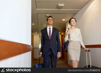 business trip and people concept - man and woman with travel bags at hotel corridor. business team with travel bags at hotel corridor