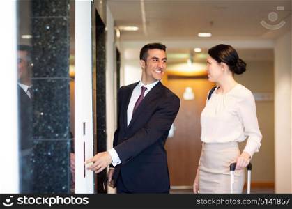 business trip and people concept - man and woman with travel bags at hotel elevator. business team with travel bags at hotel elevator