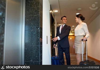 business trip and people concept - man and woman with travel bags at hotel elevator. business team with travel bags at hotel elevator