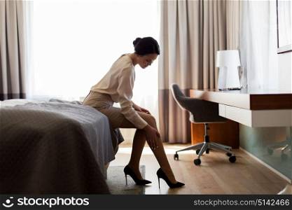 business trip and people concept - woman sitting on bed in hotel room. woman sitting on bed in hotel room