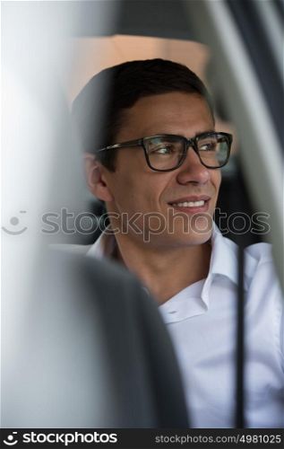 Business trip. Confident young businessman sitting in car and smiling