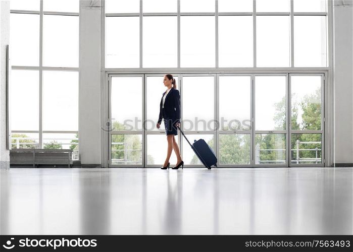 business trip, corporate and people concept - young businesswoman walking with travel bag along office building or airport. businesswoman with travel bag walking along office