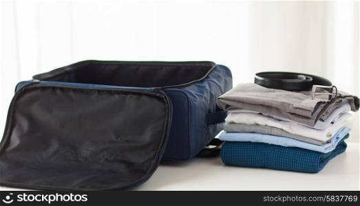 business trip, luggage and clothing concept - close up of travel bag, shirts, trousers and belt