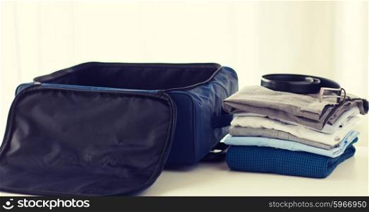 business trip, luggage and clothing concept - close up of travel bag, shirts, trousers and belt