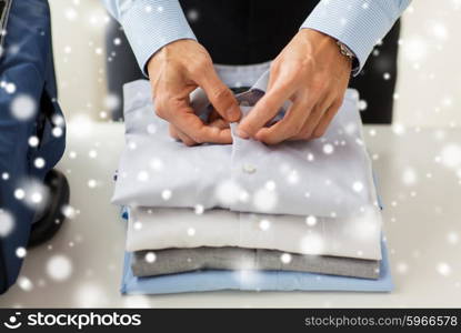 business, trip, luggage and people concept - close up of businessman packing clothes into travel bag over snow effect