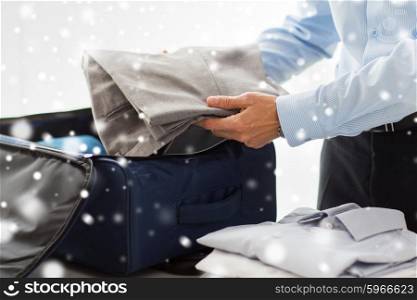 business, trip, luggage and people concept - close up of businessman packing clothes into travel bag over snow effect