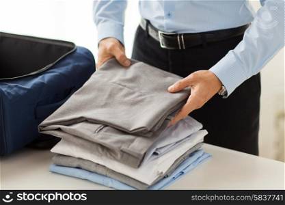 business, trip, luggage and people concept - close up of businessman packing clothes into travel bag