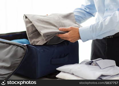 business, trip, luggage and people concept - close up of businessman packing clothes into travel bag