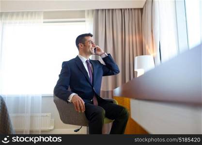 business trip, people and communication concept - businessman calling on smartphone at hotel room. businessman calling on smartphone at hotel room
