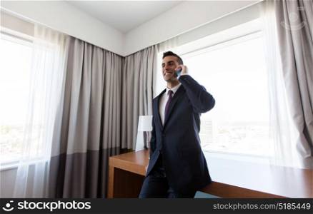 business trip, people and communication concept - businessman calling on smartphone at hotel room. businessman calling on smartphone at hotel room