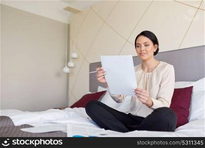 business trip, people and paperwork concept - businesswoman with papers working at hotel room. businesswoman with papers working at hotel room