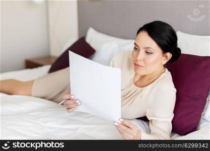 business trip, people and paperwork concept - businesswoman with papers working at hotel room. businesswoman with papers working at hotel room