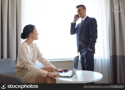 business trip, people and teamwork concept - woman working on laptop computer and man calling on smartphone at hotel room. business team with laptop working at hotel room