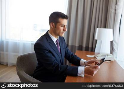 business trip, people and technology concept - businessman with tablet pc computer working at hotel room. businessman with tablet pc working at hotel room