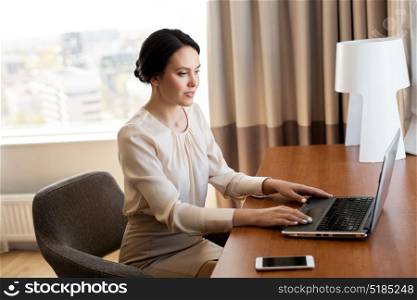 business trip, people and technology concept - businesswoman typing on laptop at hotel room. businesswoman typing on laptop at hotel room