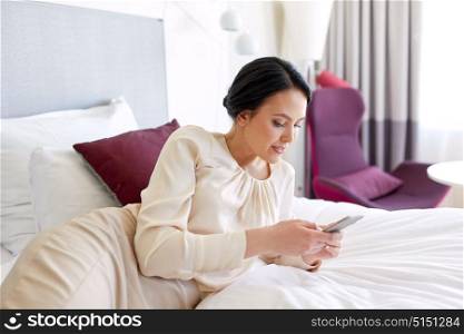 business trip, people and technology concept - businesswoman with smartphone at hotel room. businesswoman with smartphone at hotel room