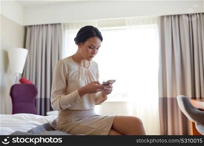 business trip, people and technology concept - businesswoman with smartphone working at hotel room. businesswoman with smartphone at hotel room