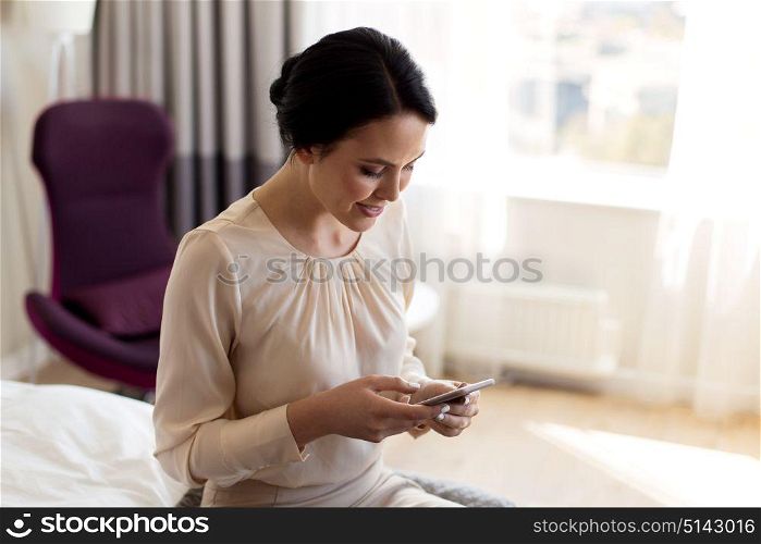 business trip, people and technology concept - happy businesswoman with smartphone working at hotel room. happy businesswoman with smartphone at hotel room