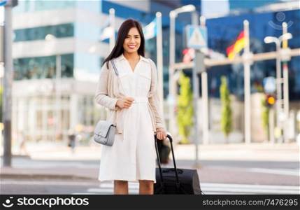 business trip, people and tourism concept - happy young asian woman with travel bag on city street. happy young asian woman with travel bag in city