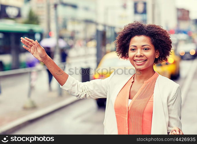 business trip, transportation and people concept - young smiling african american woman catching taxi at city street