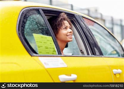 business trip, transportation and people concept - young smiling african american woman driving in taxi at city street