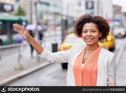 business trip, transportation and people concept - young smiling african american woman catching taxi at city street