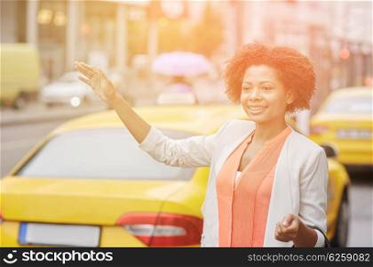 business trip, transportation and people concept - young smiling african american woman catching taxi at city street