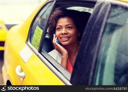 business trip, transportation, travel, gesture and people concept - young smiling african american woman calling on smartphone in taxi at city street