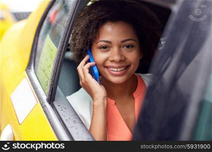 business trip, transportation, travel, gesture and people concept - young smiling african american woman calling on smartphone in taxi at city street