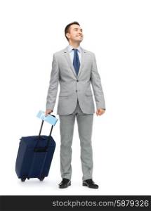 business trip, traveling, luggage and people concept - happy businessman in suit with travel bag and air ticket