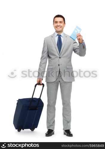 business trip, traveling, luggage and people concept - happy businessman in suit with travel bag and air ticket