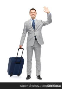 business trip, traveling, luggage, gesture and people concept - happy businessman in suit with travel bag waving hand