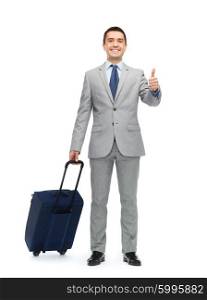 business trip, traveling, luggage, gesture and people concept - happy businessman in suit with travel bag showing thumbs up