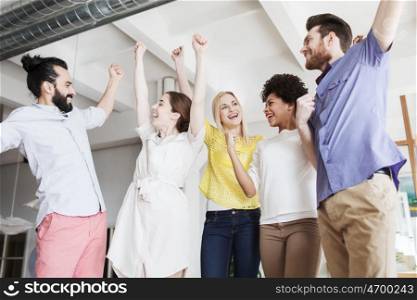 business, triumph, gesture, people and teamwork concept - happy creative team raising hands up and celebrating victory in office
