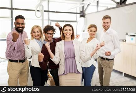 business, triumph, gesture, people and teamwork concept - happy creative team showing fists and celebrating victory at office
