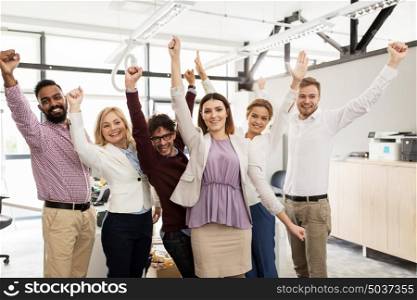 business, triumph, gesture, people and teamwork concept - happy creative team showing fists and celebrating victory at office. happy business team celebrating victory at office