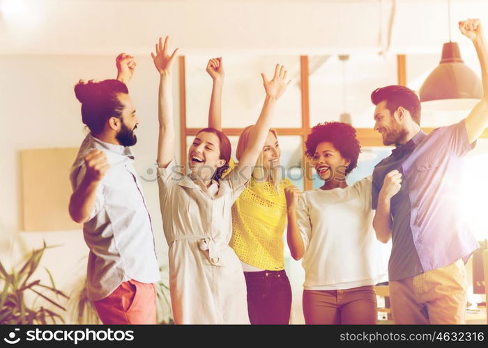 business, triumph, gesture, people and teamwork concept - happy international creative team raising hands up and celebrating victory in office