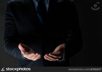 business, virtual reality, people and advertisement concept - close up of businessman in suit holding something imaginary on palms of his hands