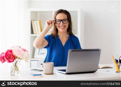 business, vision and people concept - happy smiling woman with laptop computer working at home or office. happy woman with laptop working at home or office