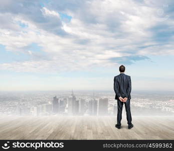 Business vision. Back view of confident businessman looking at city